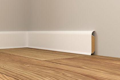 Weiße Sockelleiste an einer grauen Wand, die eine hölzerne Bodenleiste abdeckt. Der Boden ist ein heller Holzfußboden mit deutlicher Maserung.